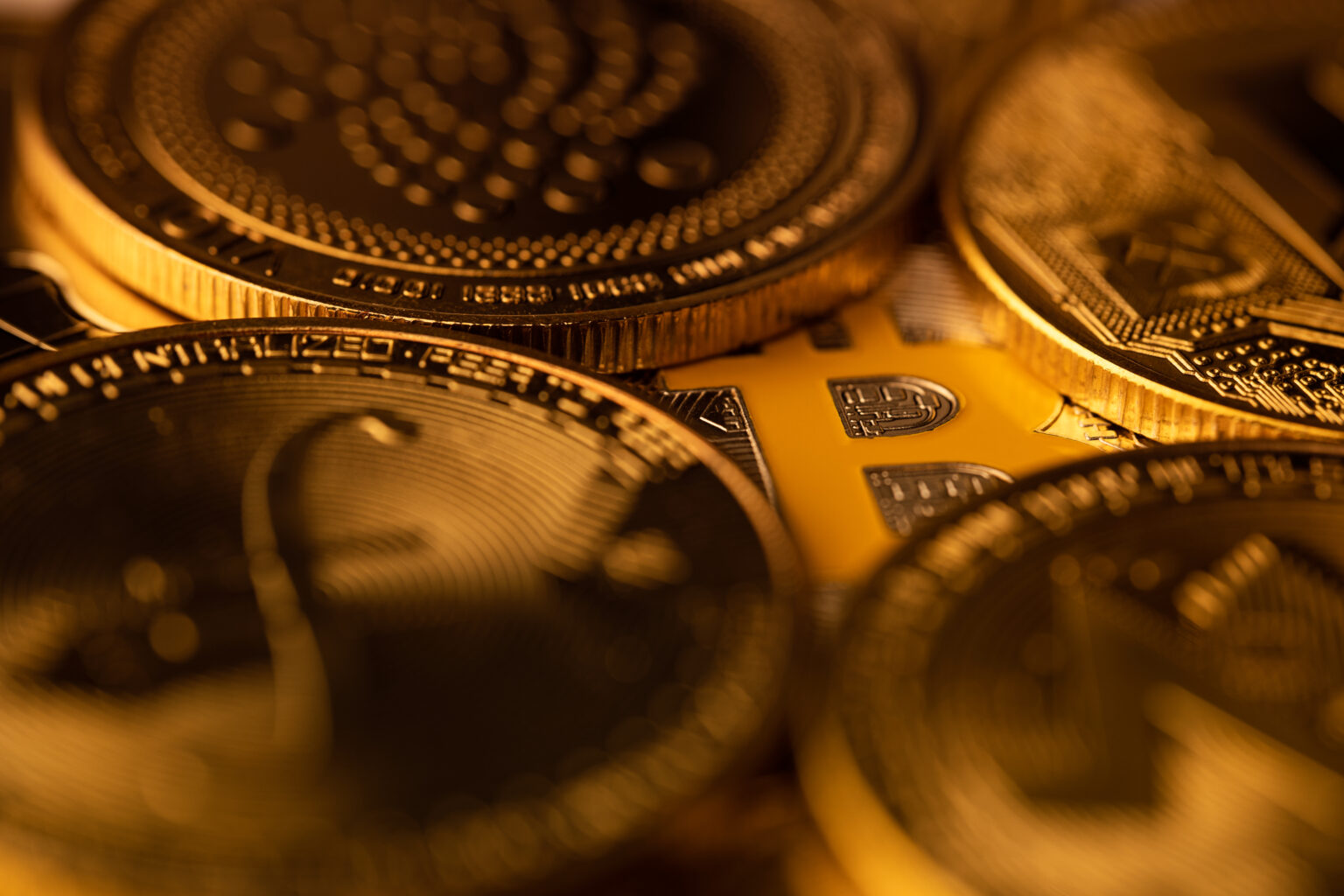 top view macro closeup of crypto bitcoin silver coin on top of a pile of other golden cryptocurrency coins